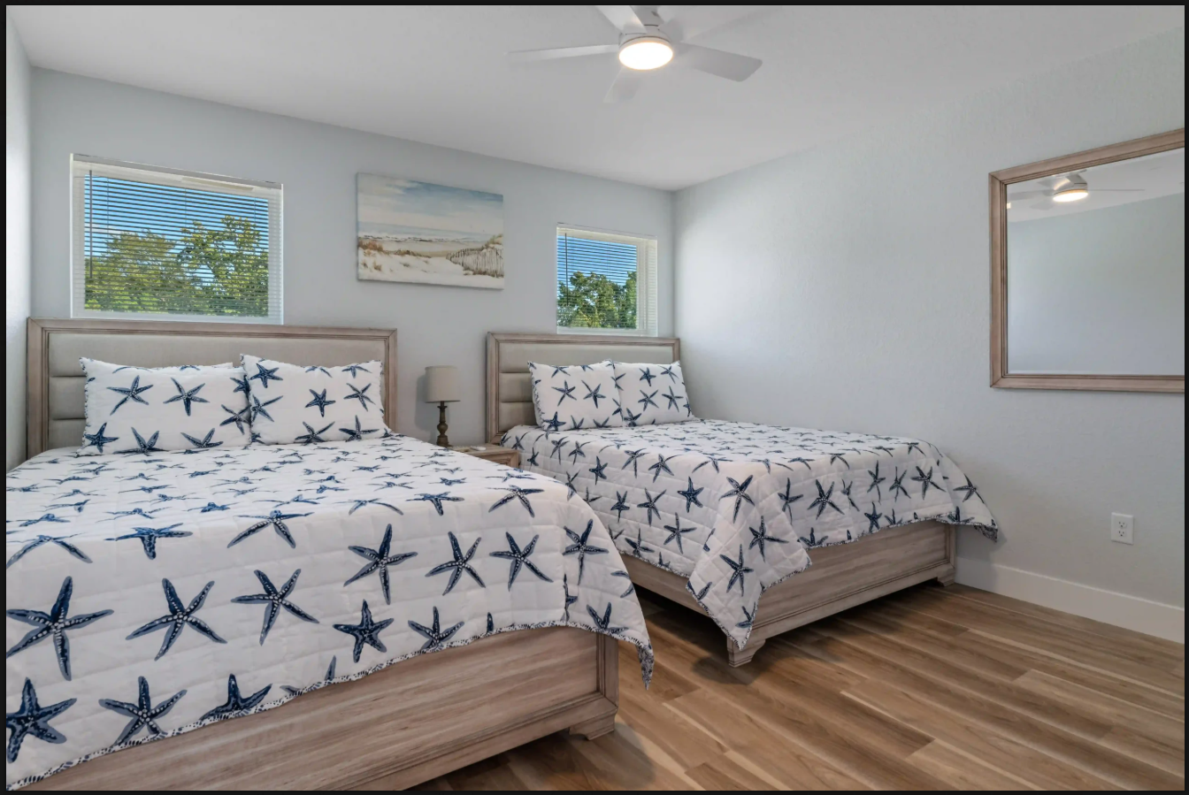 Beach-themed bedroom with two twin beds, starfish bedding, and light wood floors