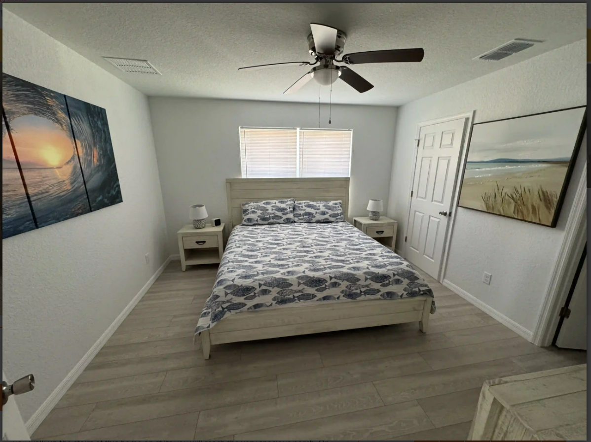 Bright bedroom with a bed, ceiling fan, nightstand, wall art, and white closet doors