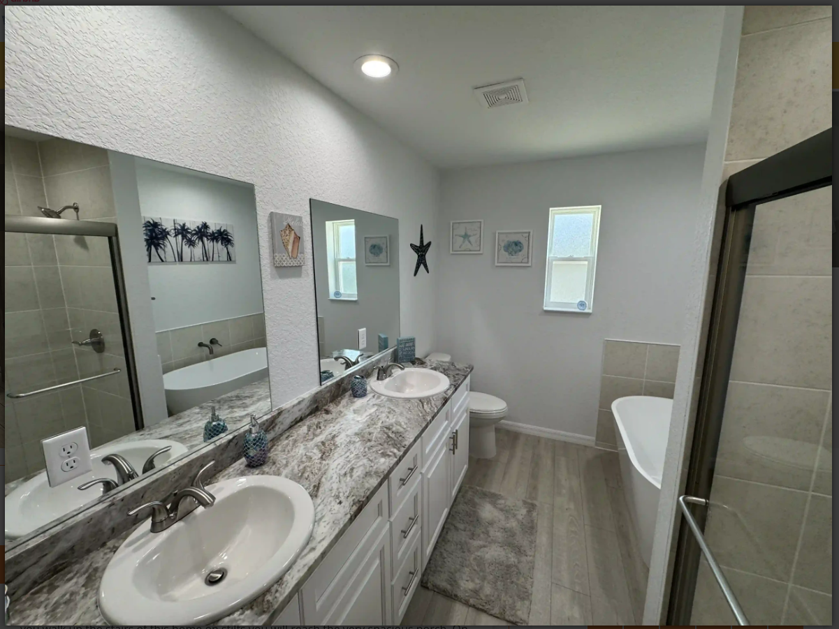 Bright modern bathroom with white vanity, large mirror, and a glass shower enclosure