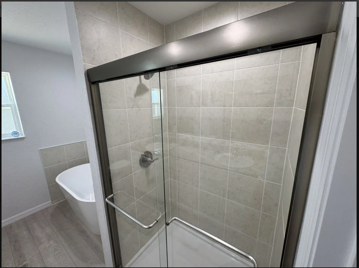 Bathroom with glass shower enclosure and tiled walls beside a bathtub