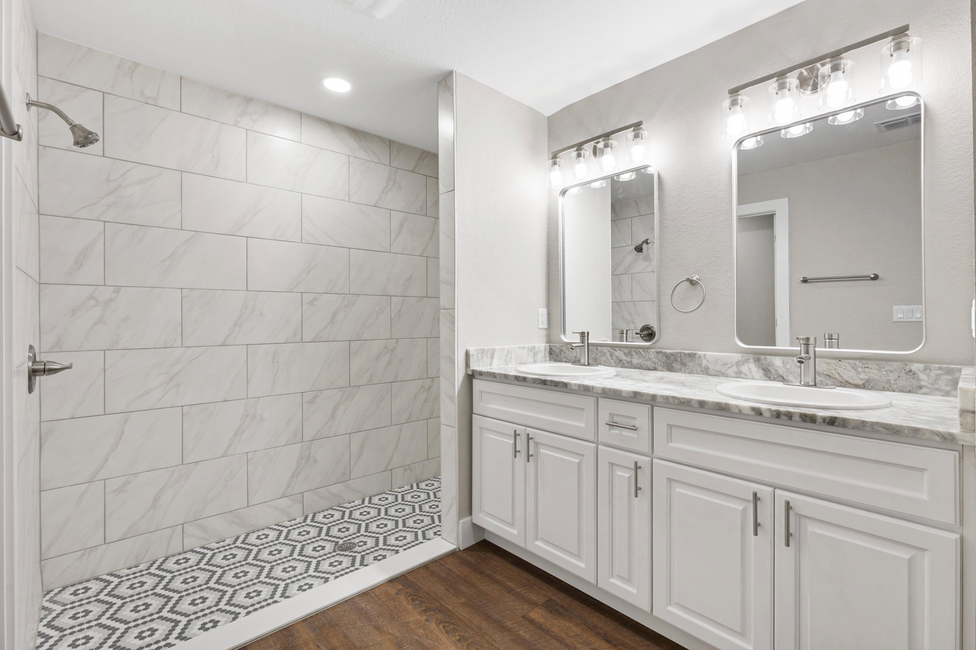 Modern white bathroom with tiled walk-in shower, double vanity, and marble countertops
