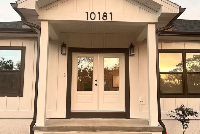 Front entrance of a house with white double doors and the number 10181 above the porch.