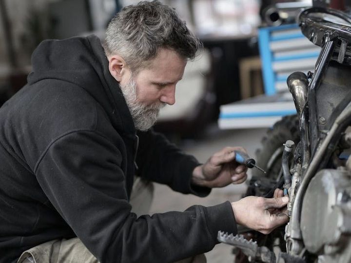 A man is working on a motorcycle in a garage.