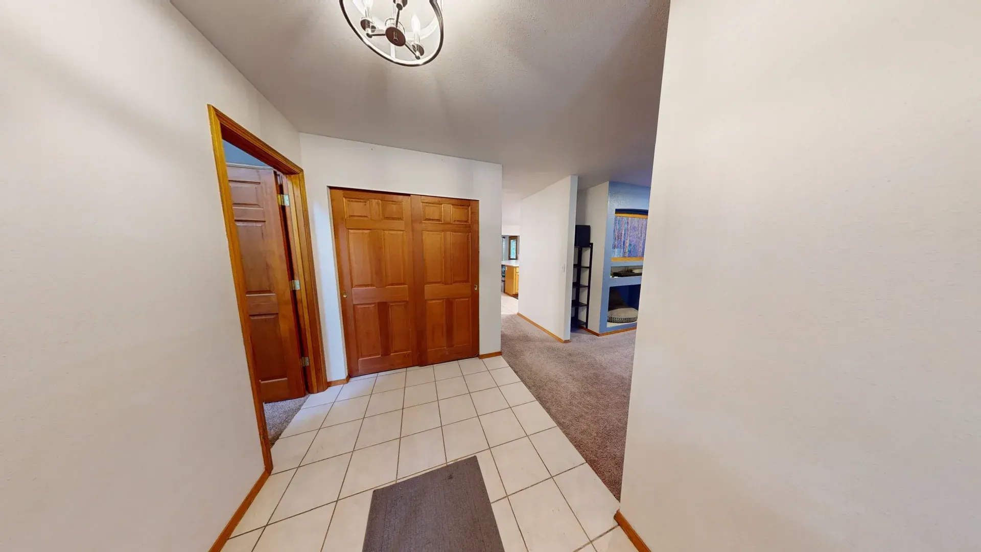 Hallway with tile floor, brown closet doors, and door on the left.