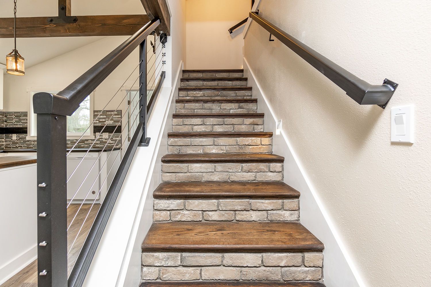 Staircase with brick-style risers and wooden treads. Black metal handrails with cable accents.