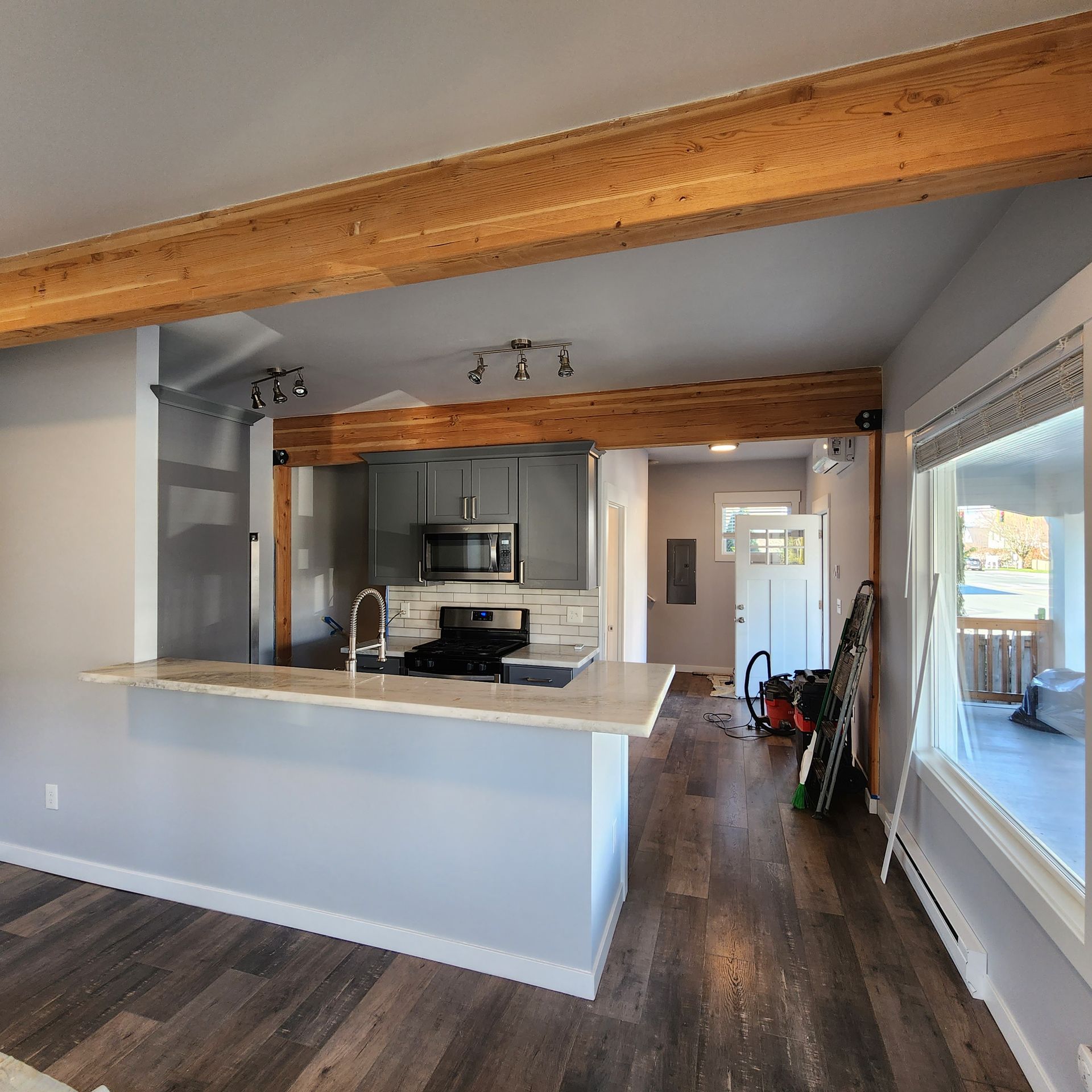 Modern kitchen with gray cabinets, wooden beams, and a breakfast bar.