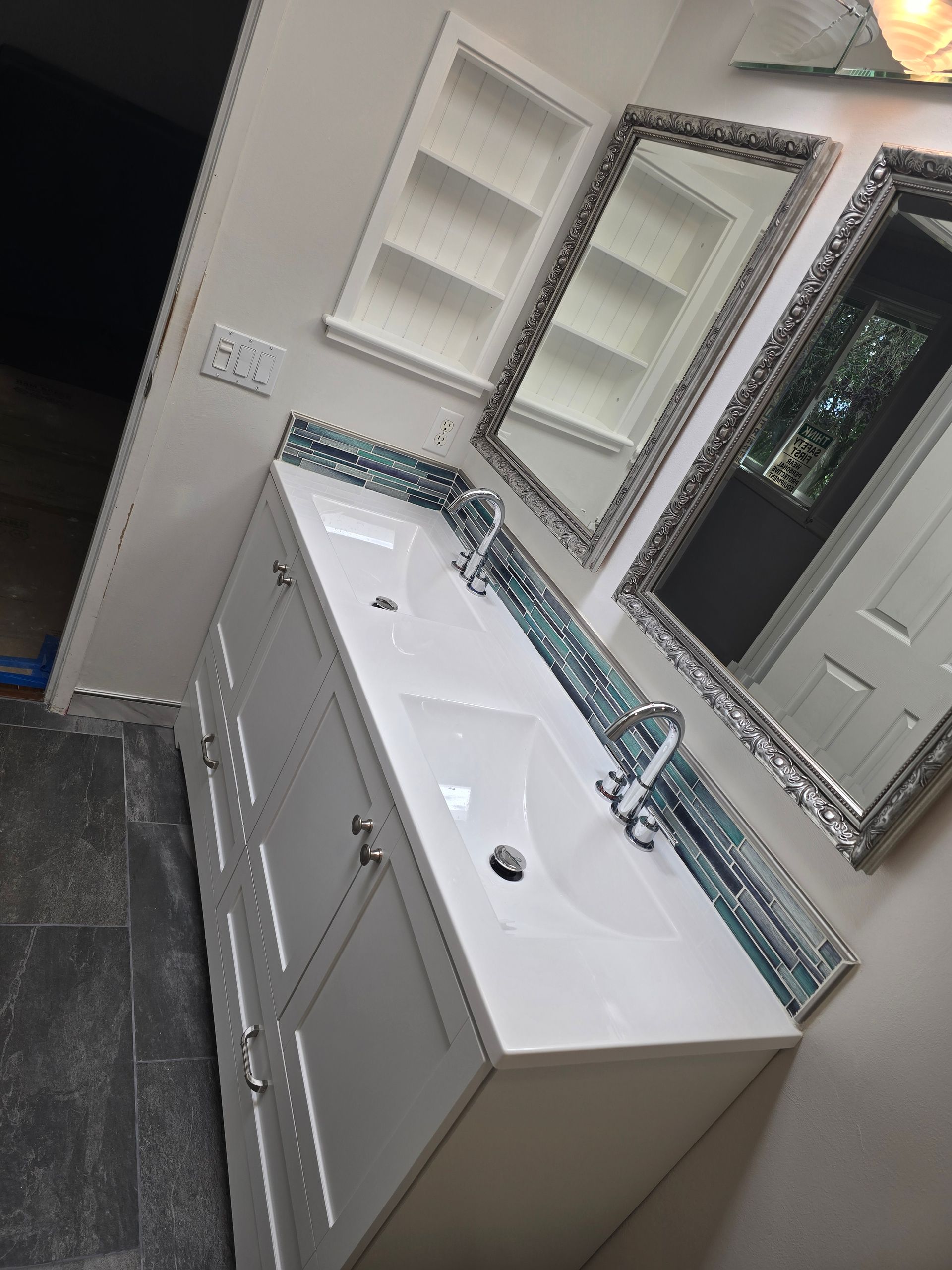 White bathroom vanity with two sinks, two mirrors, and a recessed shelf.