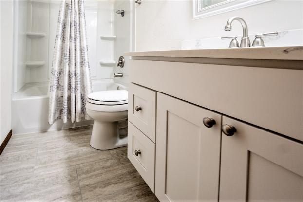 Bathroom interior with white vanity, toilet, and shower/tub. Light gray tiled floor.