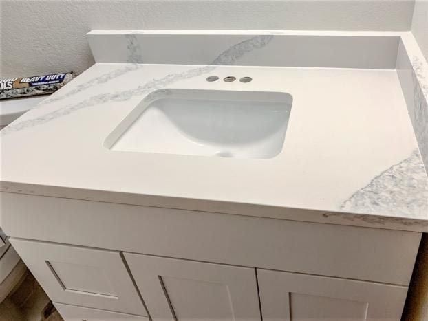White bathroom vanity with white countertop and integrated sink. Three faucet holes.