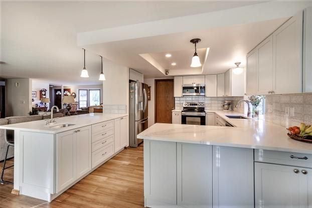 White kitchen with an island, countertops, cabinets, and wood flooring.