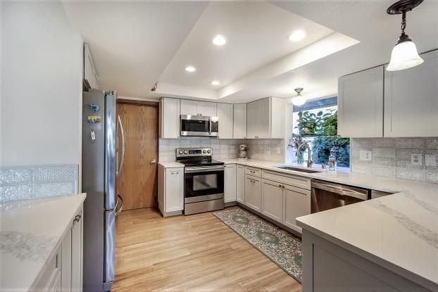 Kitchen with light gray cabinets, stainless steel appliances, and wood flooring.