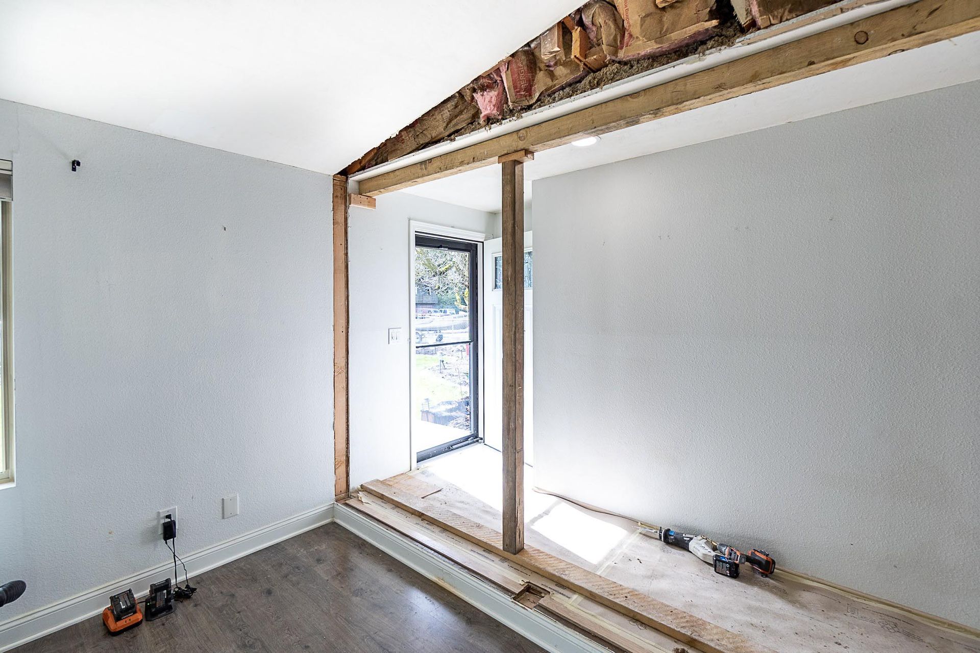 Room renovation with a doorway being framed, exposing wood and drywall.