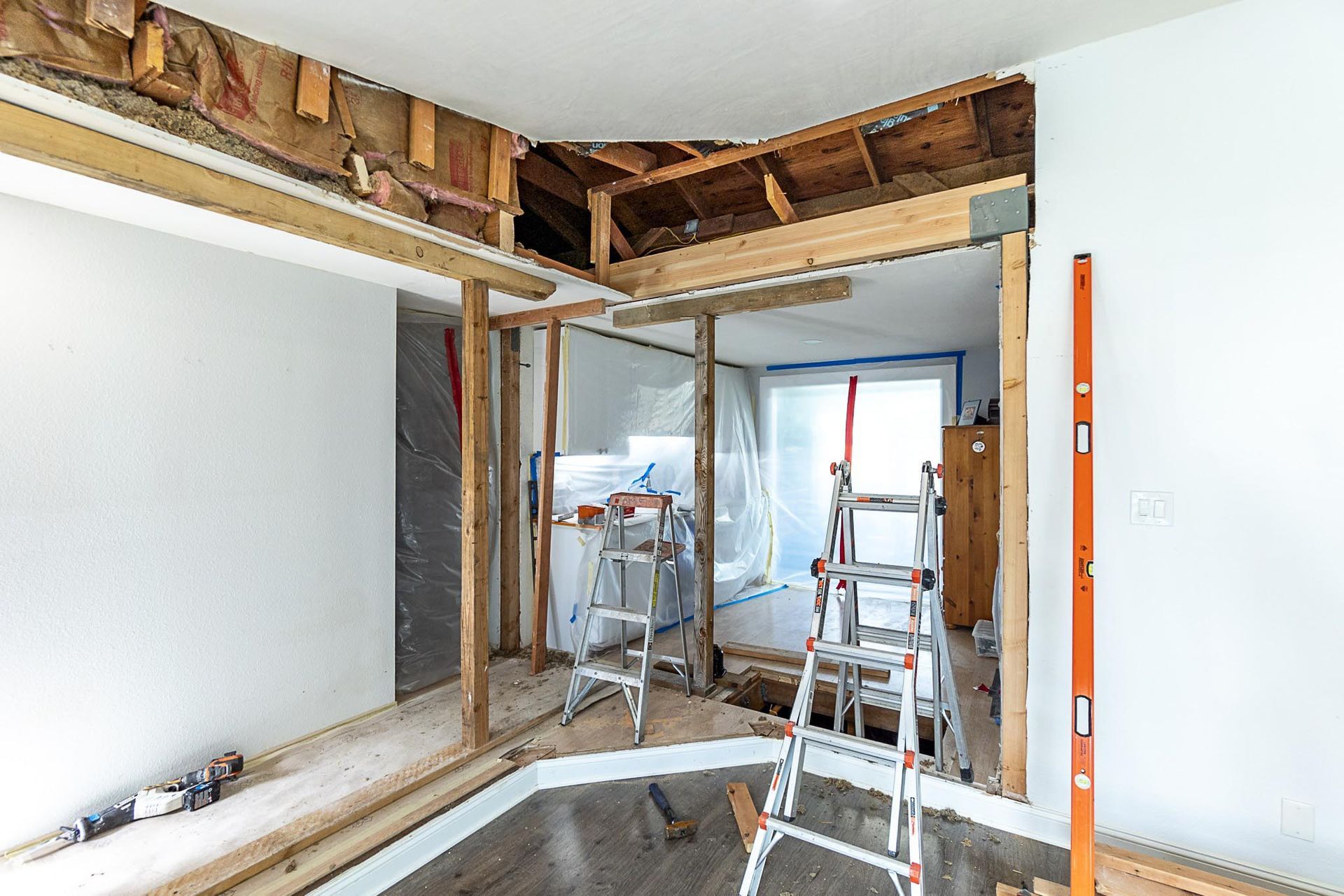 Interior room undergoing renovation, exposed framing, ladders, and building materials visible.