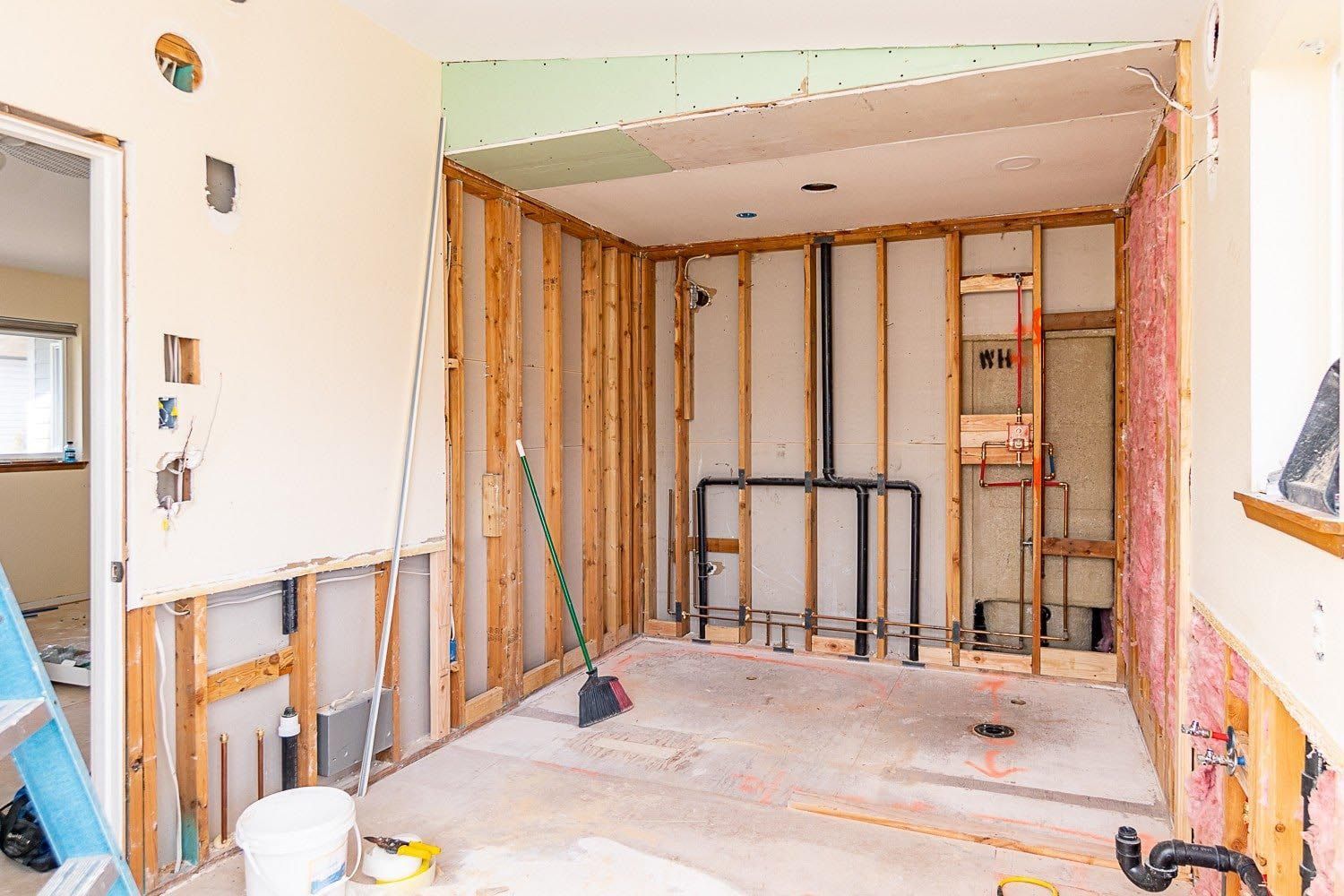 Room renovation with exposed wooden studs, insulation, and plumbing.