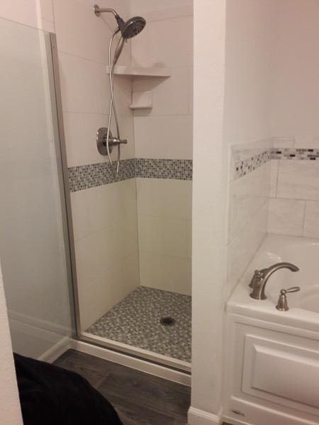 Modern bathroom with a glass-enclosed shower, mosaic tile border, and a built-in bathtub.