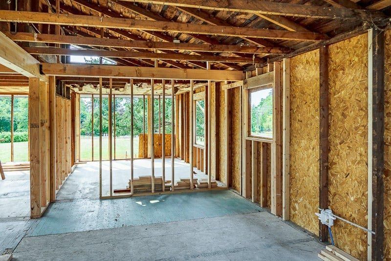 Interior of a building under construction, wooden framing, exposed walls, window openings, unfinished floor.