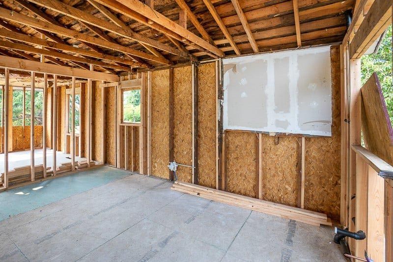 Unfinished room with wood framing, OSB walls, and a sheet of drywall on one wall.