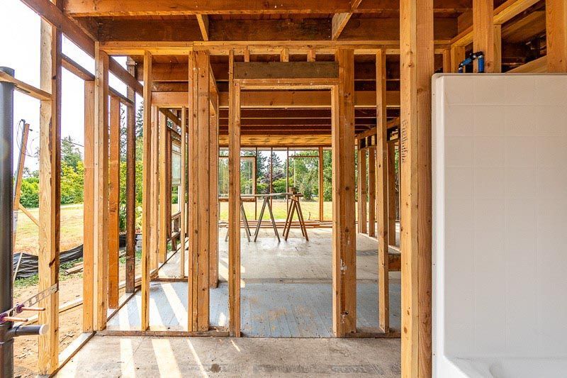 Interior view of a building under construction, framed with exposed wooden studs.