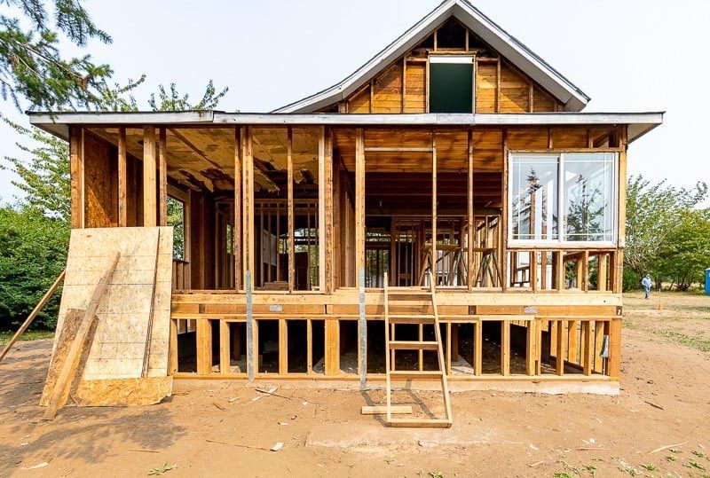 Wood frame of a house under construction; exposed beams, open spaces, and window frames.
