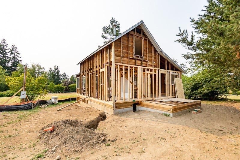 House under construction; exposed wooden frame; dirt yard.