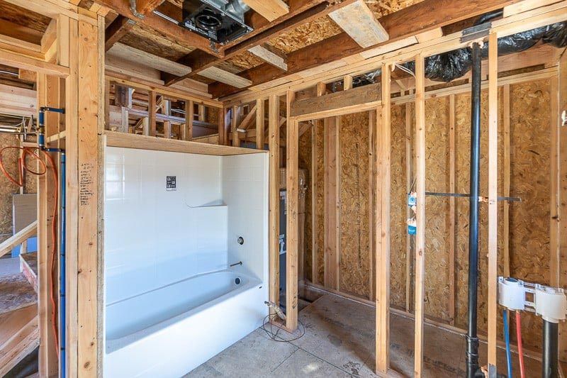 Bathroom under construction, with wooden frame, tub, and exposed plumbing.