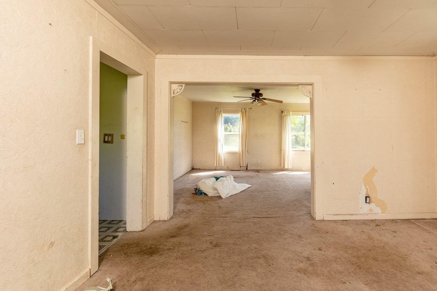 Empty, dirty interior rooms. Beige walls, stained carpet, doorways.