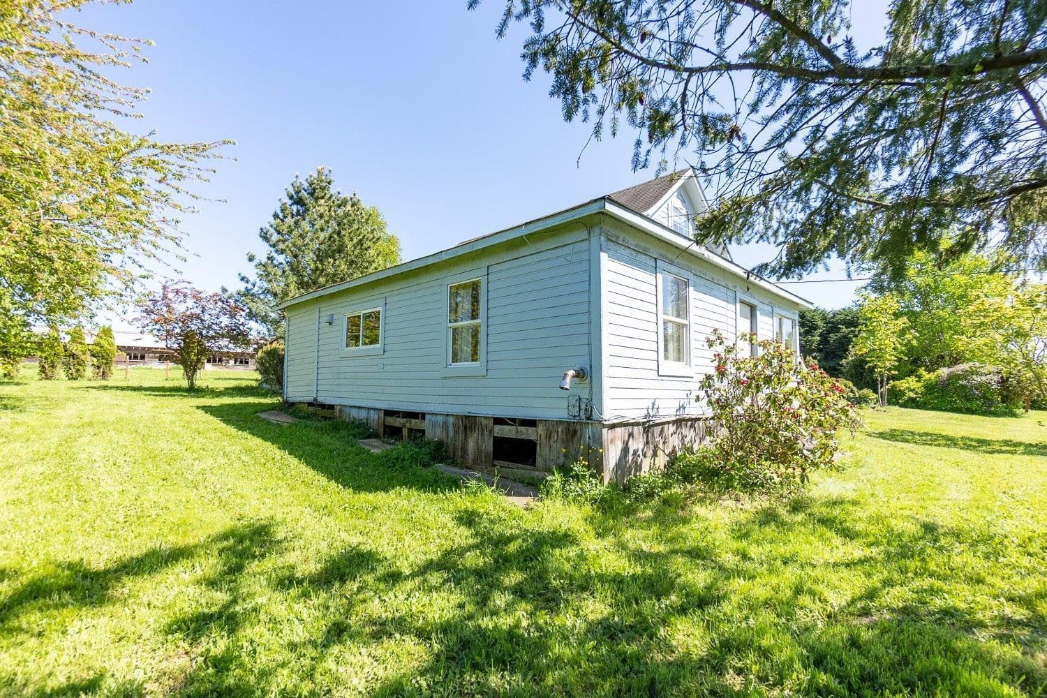 Light blue house with white trim, set on a grassy lot under a sunny sky.