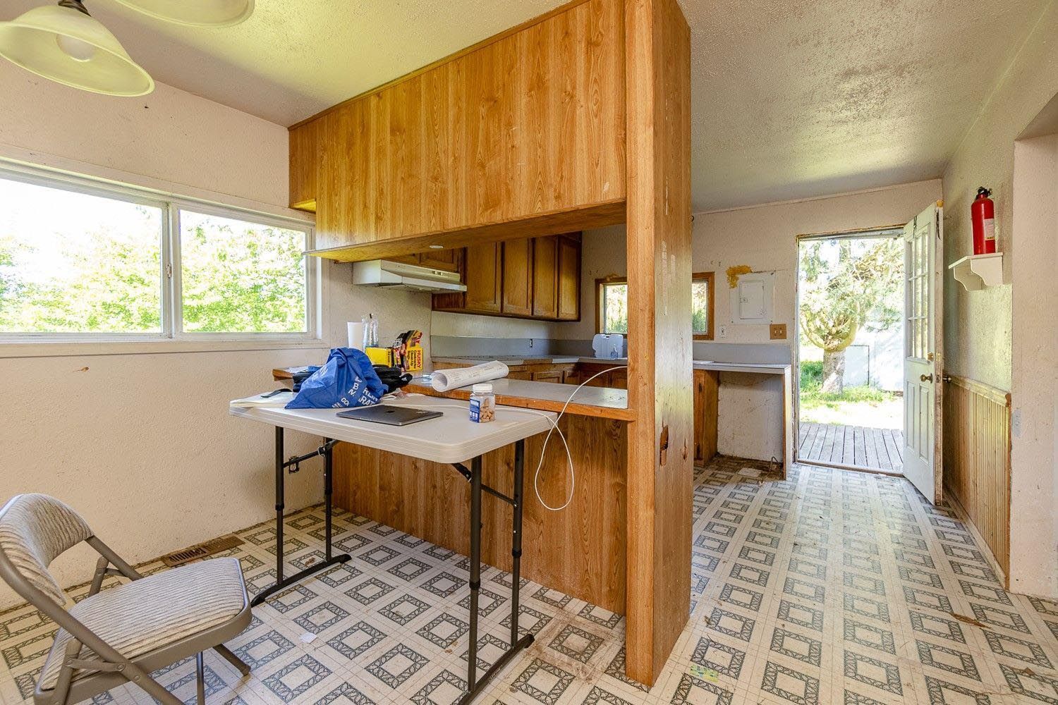 Kitchen with wood paneling, countertops, a folding table, and open doorway to backyard.