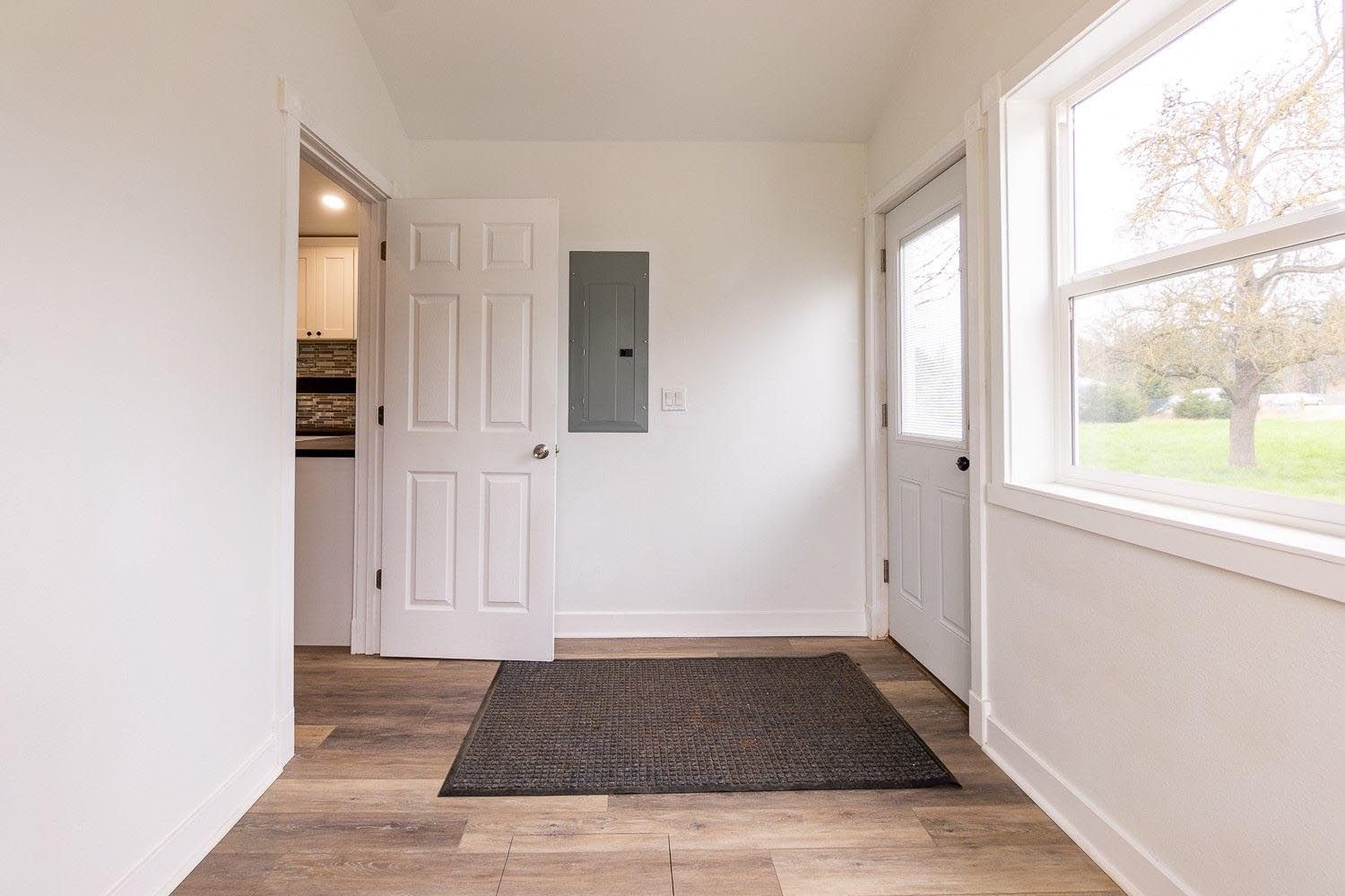 Interior doorway with a rug, white walls, wood-look floor, window, and exterior door.