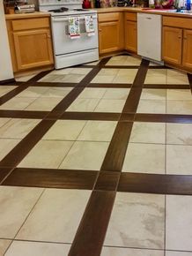 Kitchen floor with cream and brown tile in a grid pattern. Wooden cabinets and white appliances.