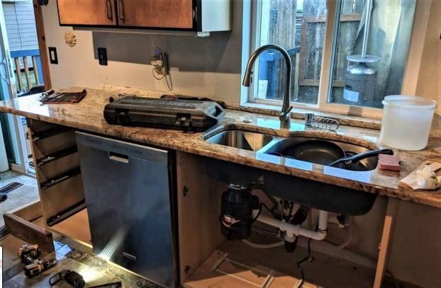 Kitchen renovation with exposed cabinets, dishwasher, sink, granite countertop, and faucet.