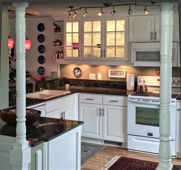 White kitchen with granite countertops, track lighting, cabinets, and a white stove.