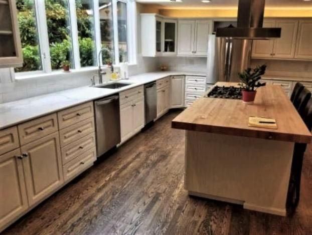 Kitchen with white cabinets, stainless steel appliances, and wood island and flooring.