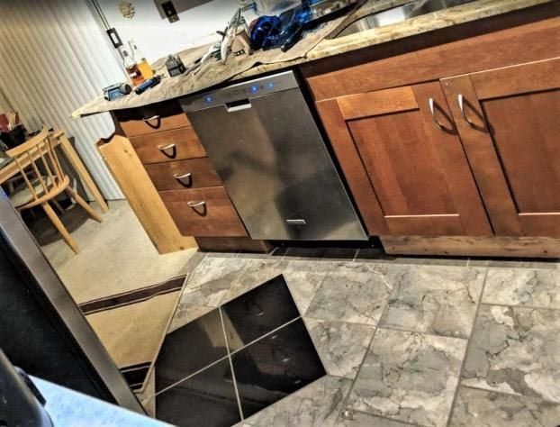 Kitchen with wood cabinets, stainless steel dishwasher, and patterned tile floor.