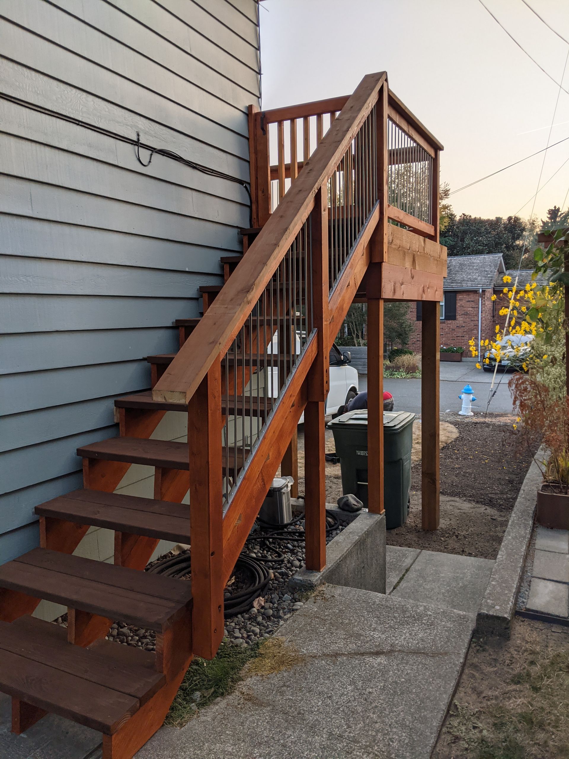 Wooden staircase leading up to a small deck attached to a light blue building.