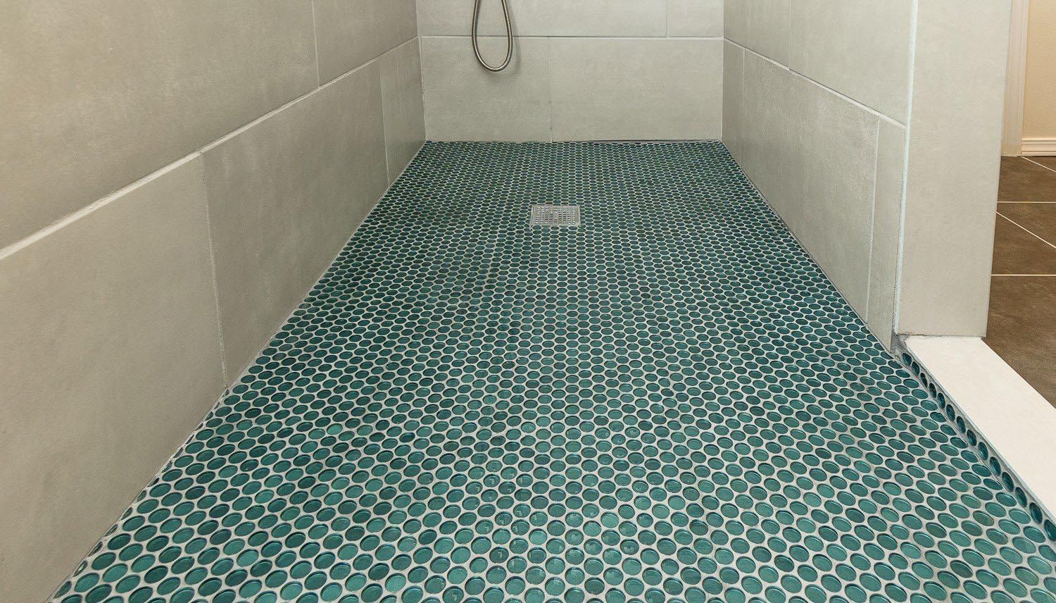 Shower floor with teal hexagon tiles and gray walls.