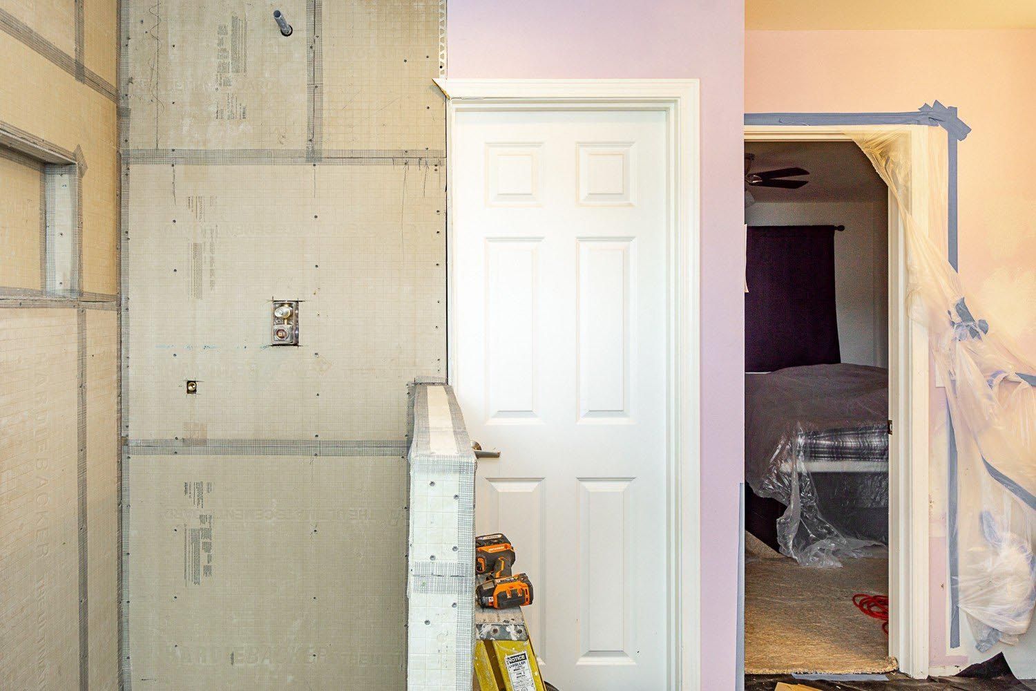 Room renovation: unfinished wall with exposed concrete panels, white door, doorway to bedroom.