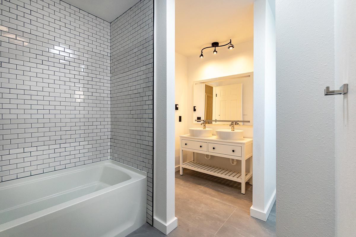 Modern bathroom with white subway tile, a bathtub, and a double-sink vanity.