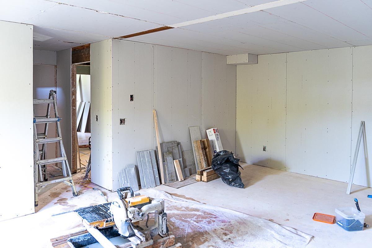 Room under renovation with drywall and construction materials scattered on the floor.