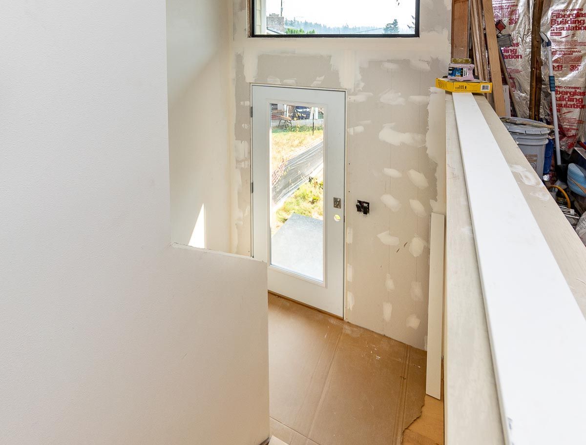 Interior view of an unfinished room with a doorway and a white railing, likely under construction.