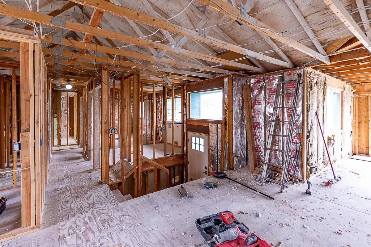 Interior of a house under construction; exposed wooden frames, insulation, and tools.