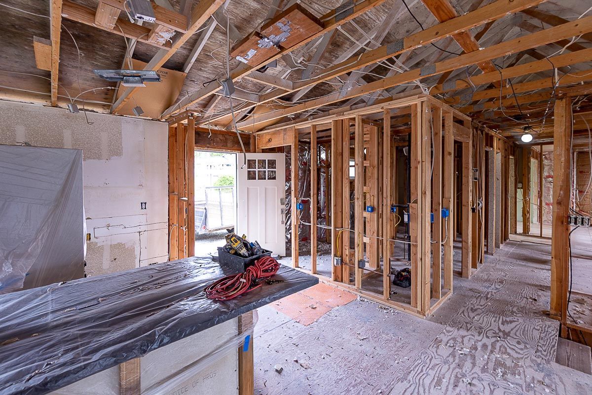 Interior of a house under construction with exposed wooden framing, insulation, and tools on the floor