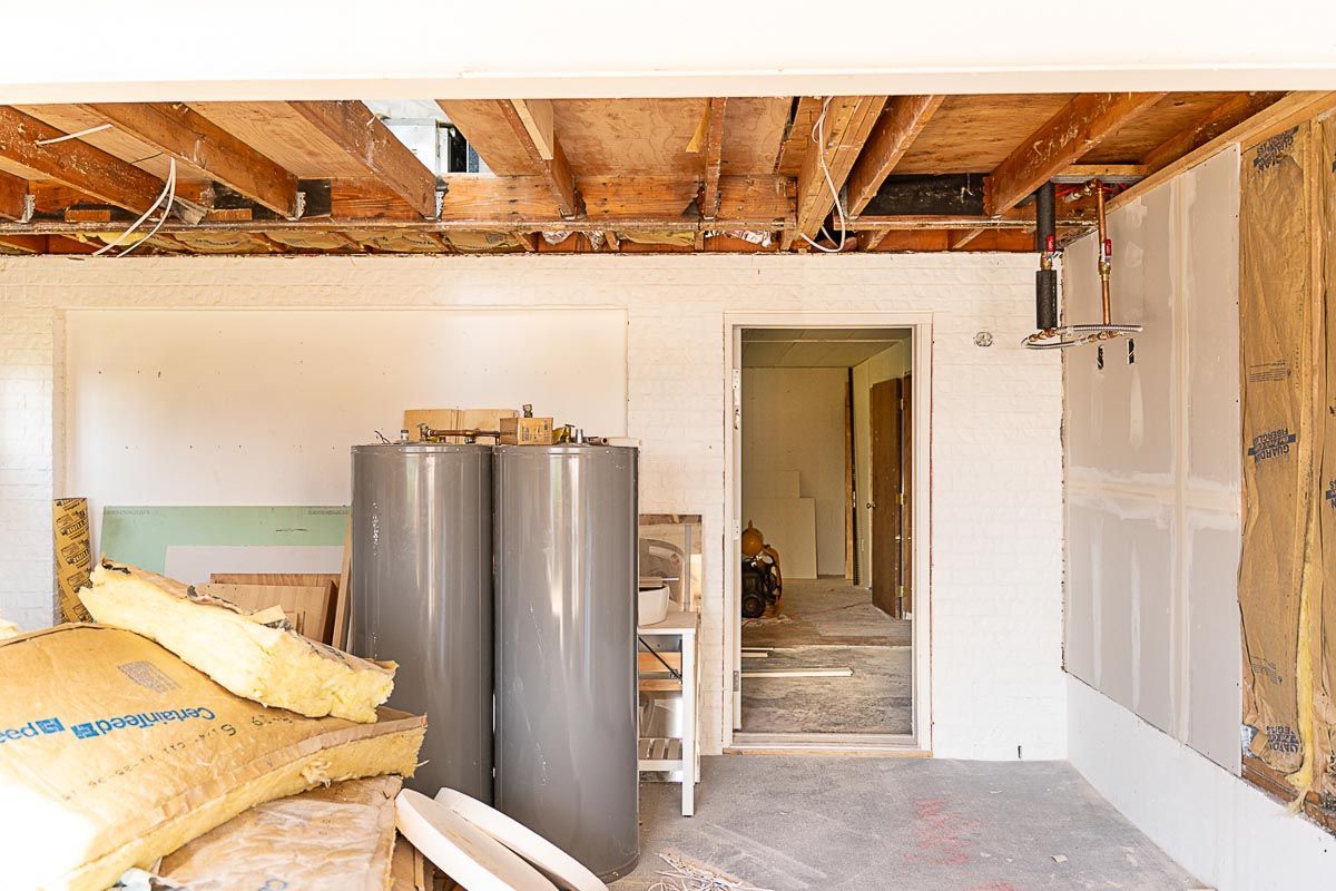 Construction site: Exposed ceiling, insulation, two water heaters, open doorway.