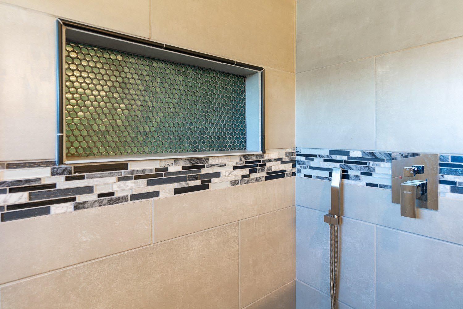 Shower with tiled walls, built-in shelf with green mosaic tile, and a modern shower fixture.