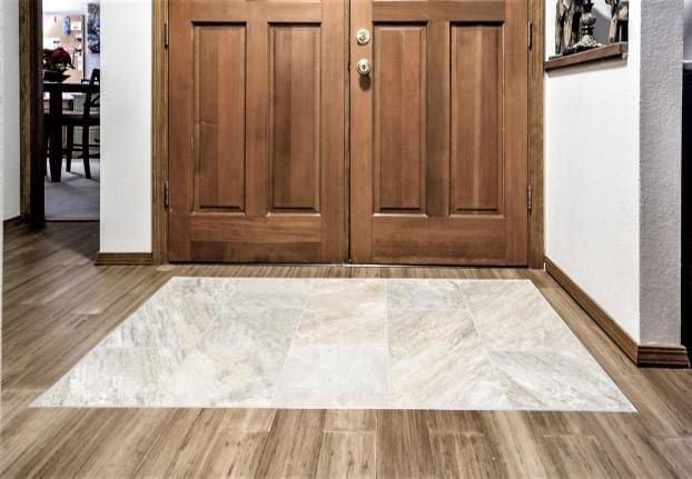 Wooden double doors with a stone tile mat in a wood-floored entryway.