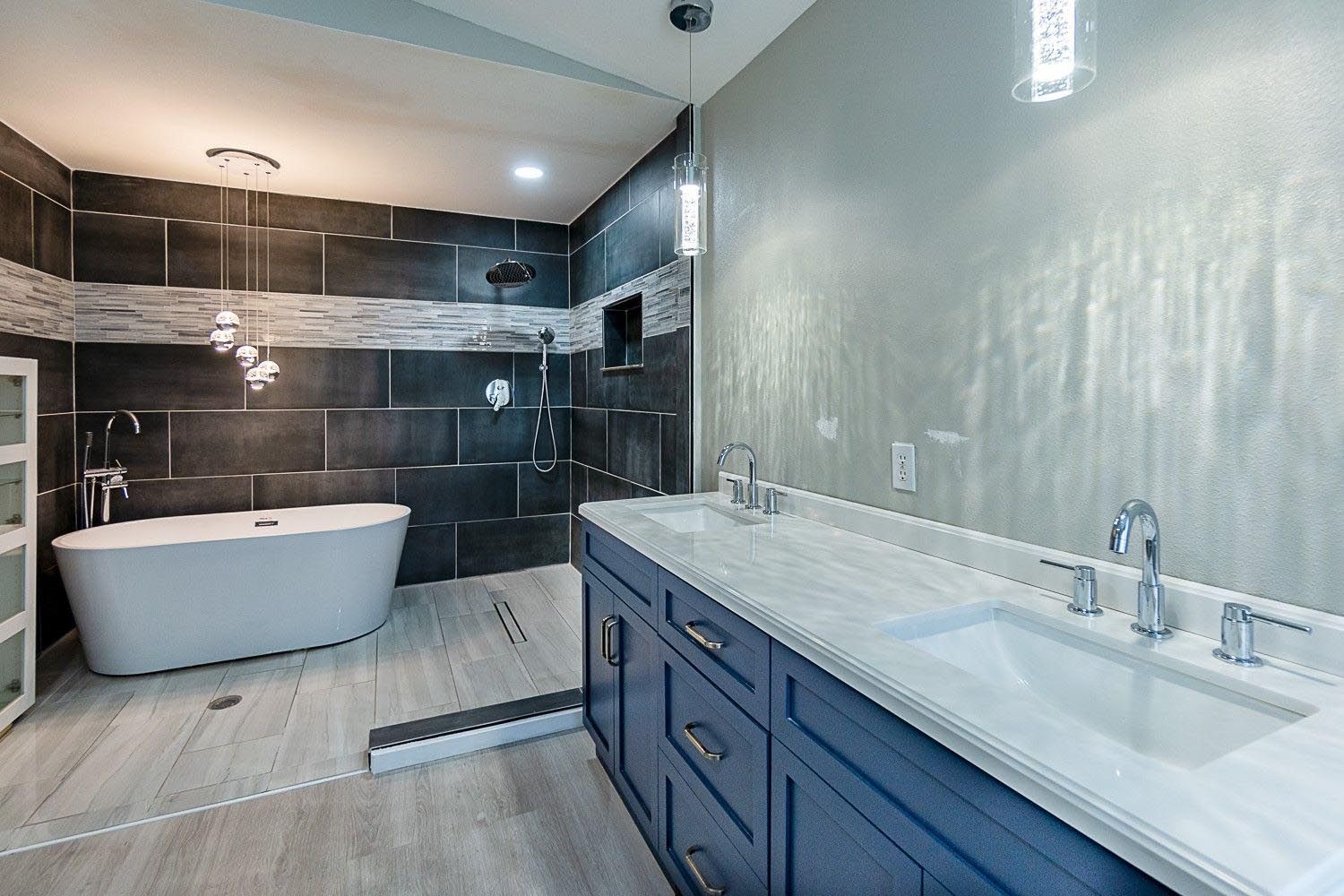 Modern bathroom with a bathtub, double vanity, and a dark tile shower.