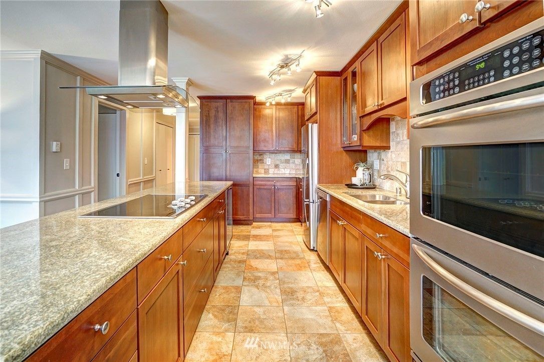 Kitchen with wood cabinets, island, stainless steel appliances, and stone floor.