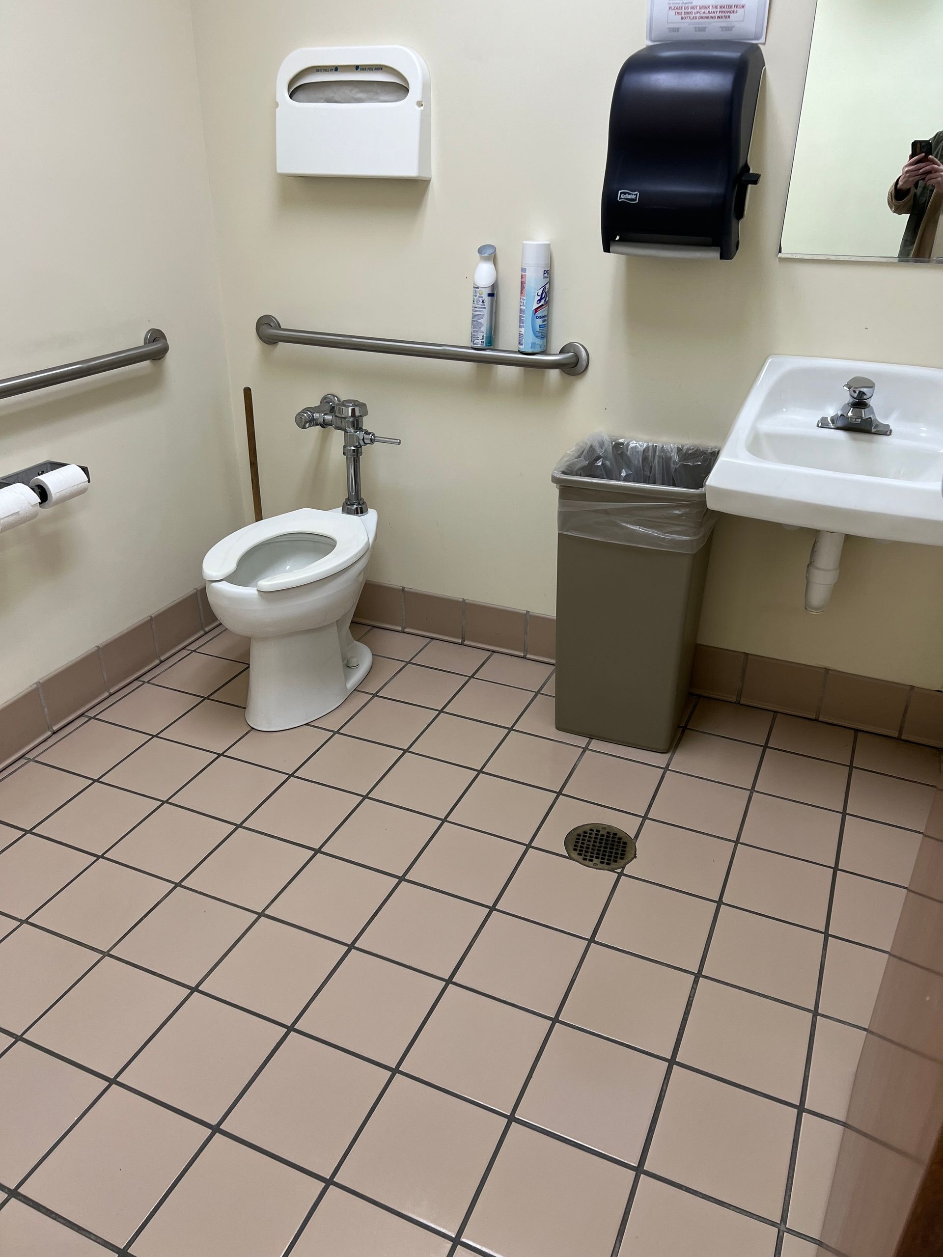 Two cleaners in a bright bathroom, one scrubbing the shower and one mopping the floor.