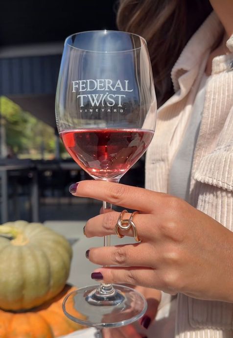 A glass of rosé wine and a vase of peach-colored flowers.