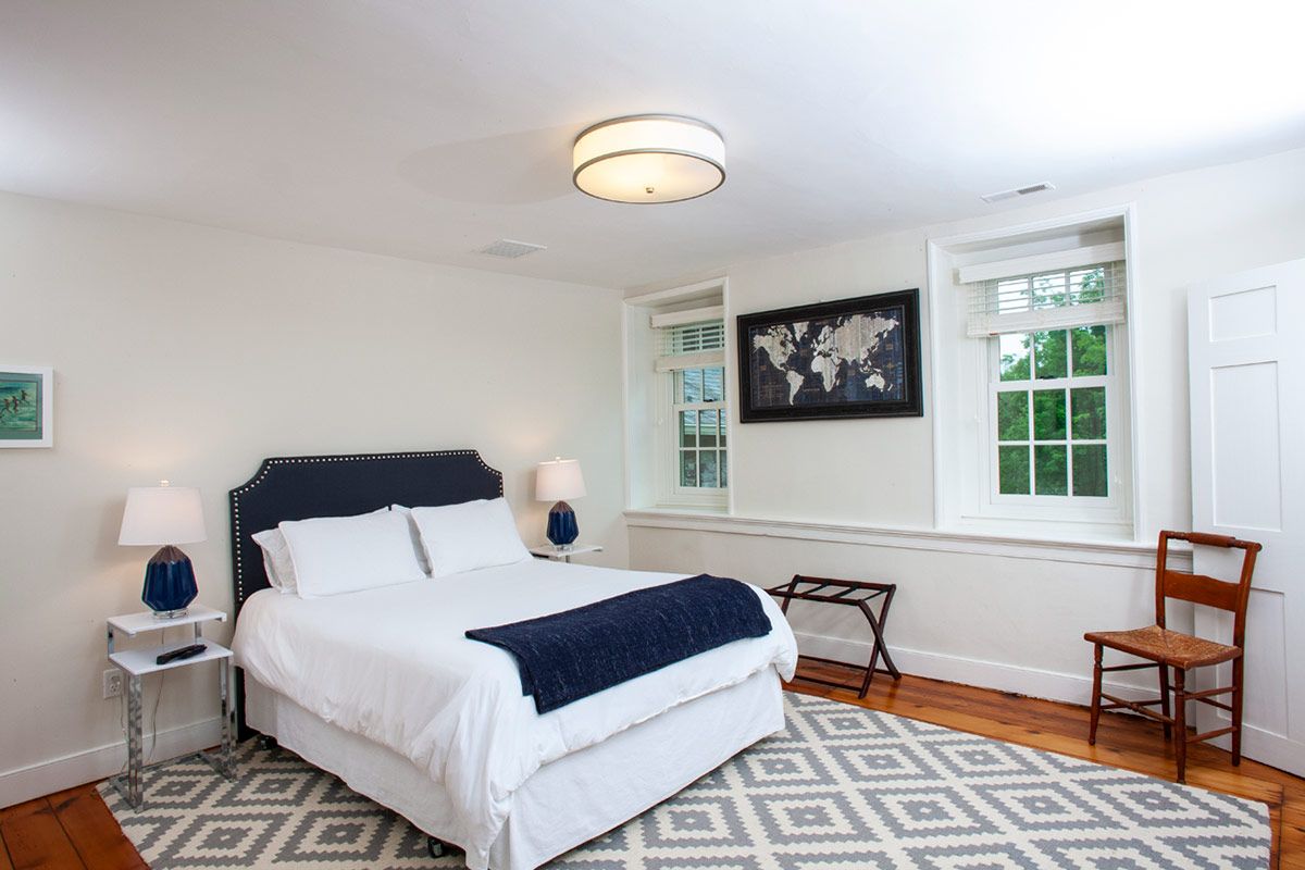 Bedroom with bed, rug, windows, and world map artwork; mostly white and blue.